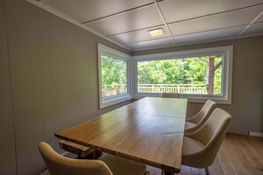 Une salle de conférence dotée d’une longue table et de six chaises, de grandes fenêtres offrant une vue sur la verdure et d’un plafond équipé d’un éclairage encastré.