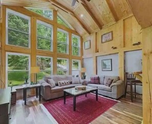 Ein gemütliches Wohnzimmer mit Kamin, großen Fenstern und einem roten Teppich.