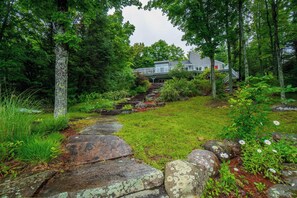 A house surrounded by a forest with a stone pathway leading to it. - Penn Lake Sweet Grass Ontario (Huntsville)