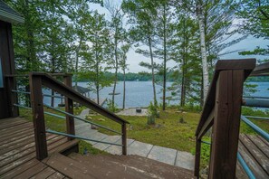 A wooden deck with a metal railing leading to a stone pathway.