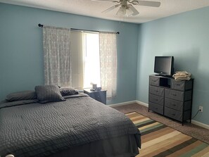 A bedroom with a bed, a dresser, a television, and a window with curtains. - Rhodes comfort stay (Whitestown)