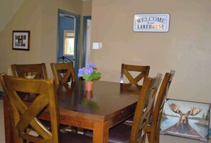 A dining table with chairs, a welcome sign, and a moose picture on the wall. - Cecebe R and R Ontario (Burk's Falls)