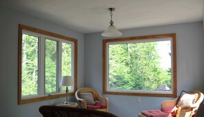 Ein Zimmer mit großen Fenstern, einer Deckenleuchte und zwei Korbstühlen.
