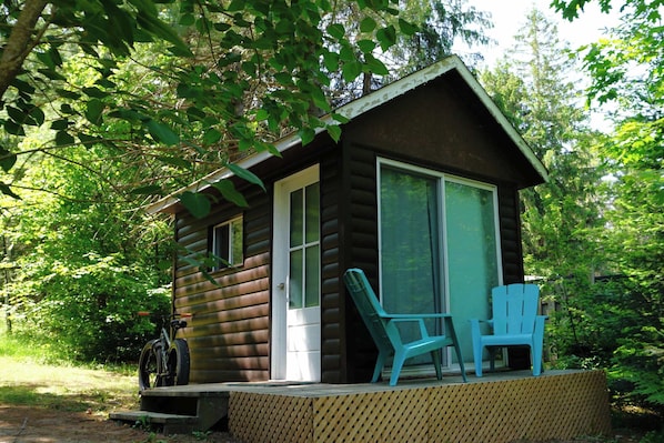 Eine Blockhütte mit Veranda, einem Fahrrad und zwei Stühlen.