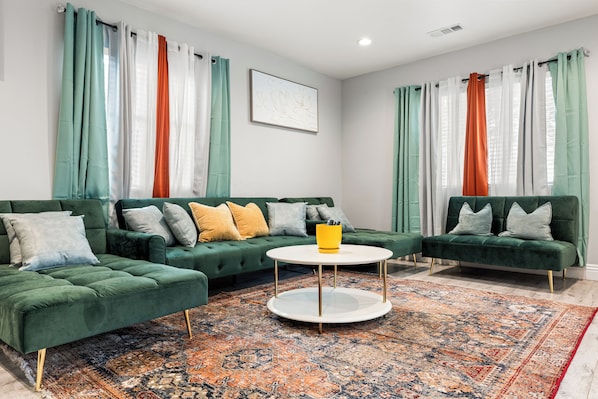 Un salon moderne avec deux canapés verts, une table basse ronde et un tapis à motifs.