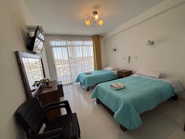 Habitación de hotel con dos camas, un escritorio, una silla, un televisor y una ventana con cortinas.