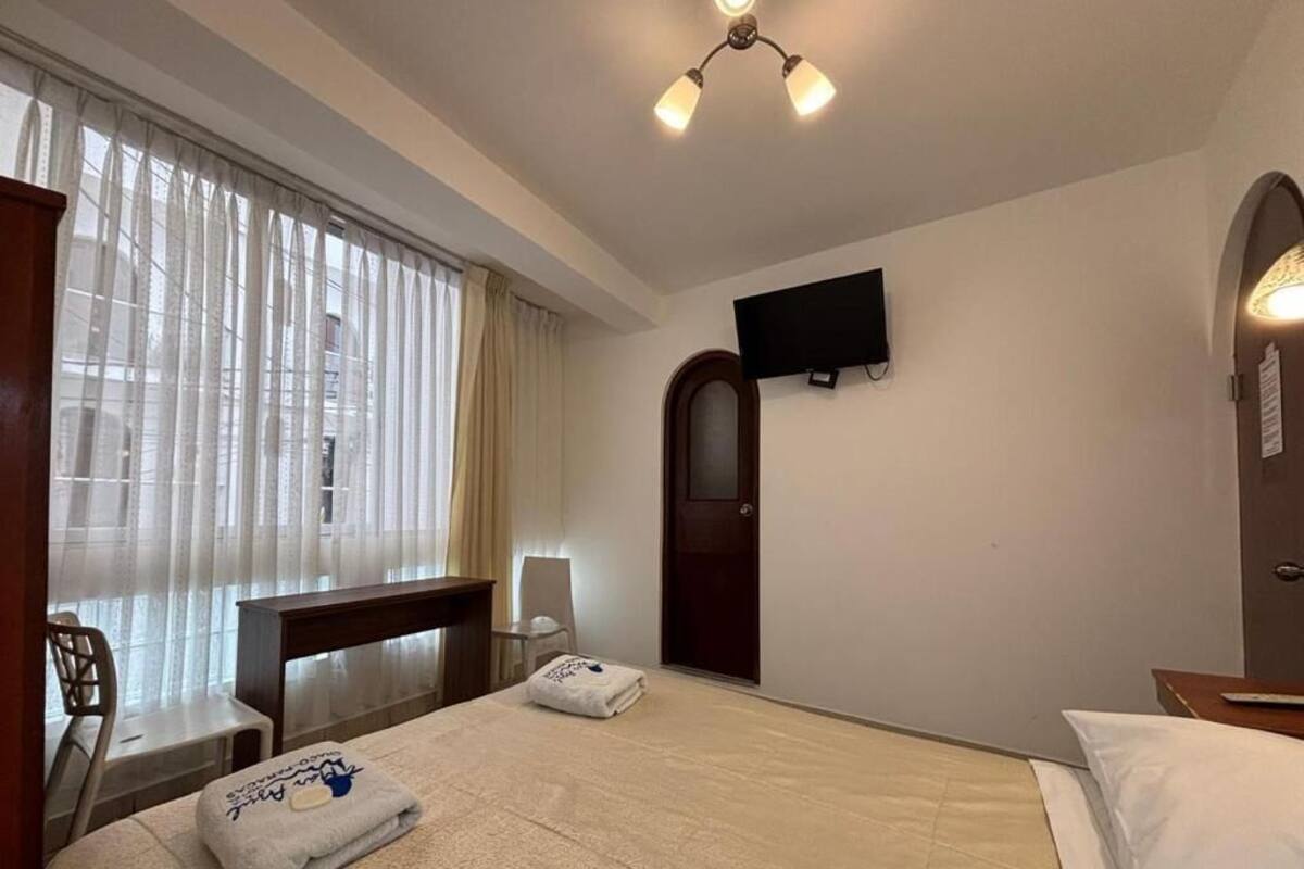 A hotel room with a bed, a desk, a chair, a television, and a door.