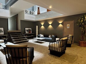 Ein modernes Wohnzimmer mit einer Couch, Sesseln, einem Couchtisch, einer Treppe und einer Pflanze.