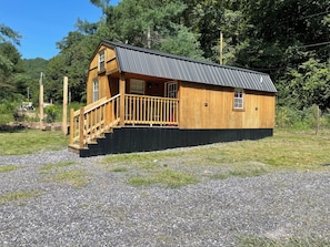 Eine Holzhütte mit einem Metalldach, einer Holzterrasse und einer Treppe, die zu einer Tür führt.