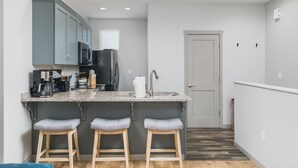 Eine kleine Küche mit einer Granit Arbeitsplatte, Edelstahlgeräten und zwei Barhocker.
