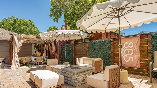 Eine Terrasse im Freien mit Steinböden, gepolsterten Sitzmöglichkeiten und Sonnenschirmen.