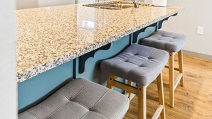 Eine Küche mit einer Granit-Arbeitsplatte, einem Spülbecken und zwei Barhocker.
