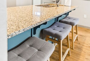 Eine Küche mit einer Granit-Arbeitsplatte, einem Spülbecken und zwei Barhocker.