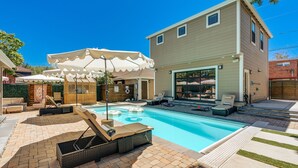 Ein Garten mit Swimmingpool, Liegestühlen und einer überdachten Terrasse.