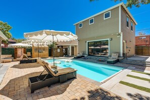Ein Garten mit Swimmingpool, Liegestühlen und einer überdachten Terrasse.