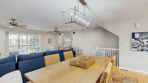 Ein Essbereich mit Holztisch, blauen Sofas und einem Deckenventilator.