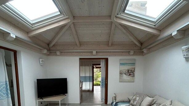 A room with a TV, a sofa, and skylights. - Costa Serena Village (Porto Rafael, Palau)