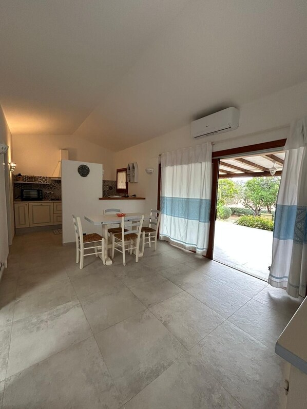 A kitchen with a microwave, a sink, and a window. There is a dining area with a table and chairs.
