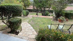 A covered patio area with a stone pathway leading to a seating area with chairs. - Costa Serena Village (Porto Rafael, Palau)