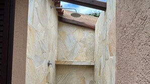 A stone-walled outdoor shower area with a wooden roof structure. - Costa Serena Village (Porto Rafael, Palau)