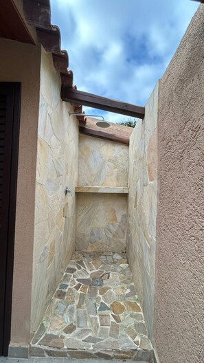 A stone-walled outdoor shower area with a wooden roof structure. - Costa Serena Village (Porto Rafael, Palau)