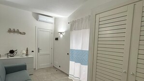A room with a sofa, a wardrobe, a door, and a curtain. - Costa Serena Village (Porto Rafael, Palau)