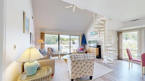 Ein geräumiges Wohnzimmer mit Treppe, großen Fenstern und Blick ins Freie.
