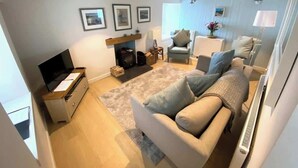 Una sala de estar con sofá, televisión, chimenea y cuadros en la pared.