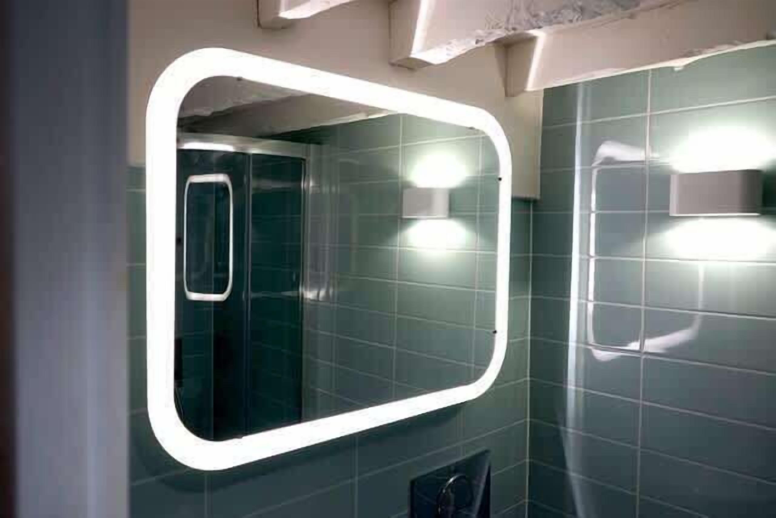 A bathroom with a large mirror, a shower, and a toilet.
