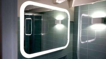 A bathroom with a large mirror, a shower, and a toilet.