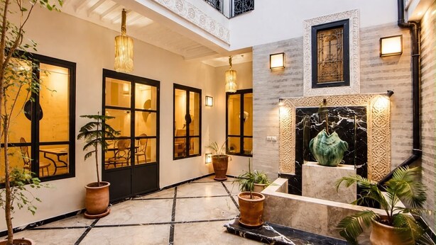 A spacious indoor area with a tiled floor, potted plants, and a decorative fireplace. - 2-bedroom riad in enchanting Marrakech with cool AC breeze (Marrakech)