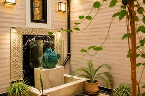 A marble-floored entrance with a decorative wall, a large blue vase, and potted plants.