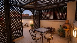 A patio with a table and chairs, a grill, and a potted plant. - 2-bedroom riad in enchanting Marrakech with cool AC breeze (Marrakech)