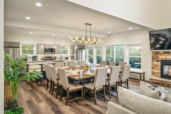 Uma cozinha espaçosa com eletrodomésticos modernos, uma sala de jantar com uma mesa grande e cadeiras, e uma lareira.