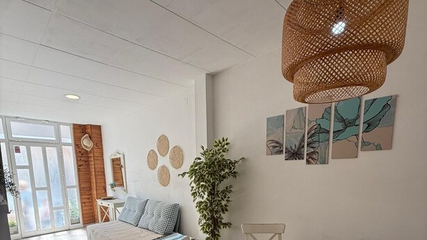 A dining area with a round table, white chairs, woven placemats, and a hanging rattan light fixture.