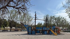 A playground with a slide, climbing structures, and a bench.