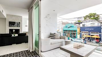 A modern living room with a sofa, a coffee table, and a view of the street.