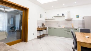 Una cocina moderna con comedor, un vidrio que da a otra habitación y una pequeña mesa con sillas.