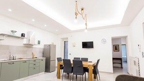 Una cocina moderna con comedor, televisor montado en la pared y una lámpara de techo.
