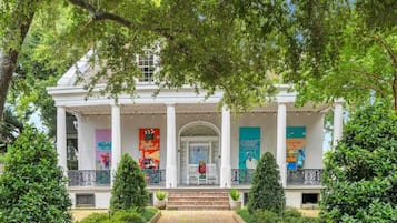 A white building with a covered porch, columns, and banners.