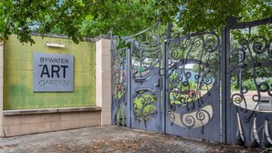 Una puerta con un letrero que dice 'BYWATER ART GARDEN'.