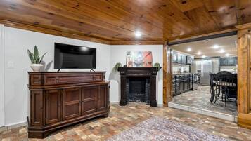 A living room with a fireplace, a television, and a kitchen visible through an open door.