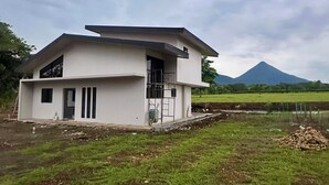 Una casa moderna de dos pisos amb teulada plana, una finestra gran i una porta.
