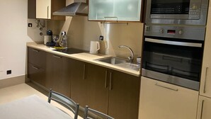 Ett modernt kök med inbyggd ugn, mikrovågsugn och vitvaror i rostfritt stål.