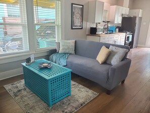 A modern living room with a grey sofa, a blue coffee table, and a kitchen in the background. - Historic Charm Meets Modern Comfort - Minutes to San Antonio Downtown/Riverwalk (San Antonio)