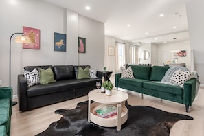 Ein modernes Wohnzimmer mit zwei Sofas, einem Couchtisch und Kunstwerken an den Wänden.
