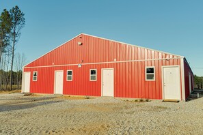 Une grange rouge avec deux portes et des fenêtres, entourée de gravier.