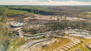 Vue aérienne d’une zone minière comprenant plusieurs sites d’extraction et un paysage boisé en arrière-plan.