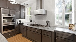 A modern kitchen with built-in appliances, a large island, and a view through the window. - Villa Bella (Minneapolis)