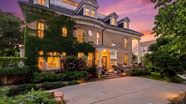 A large, two-story house with a wrap-around porch, a well-maintained garden, and a driveway. - Villa Bella (Minneapolis)